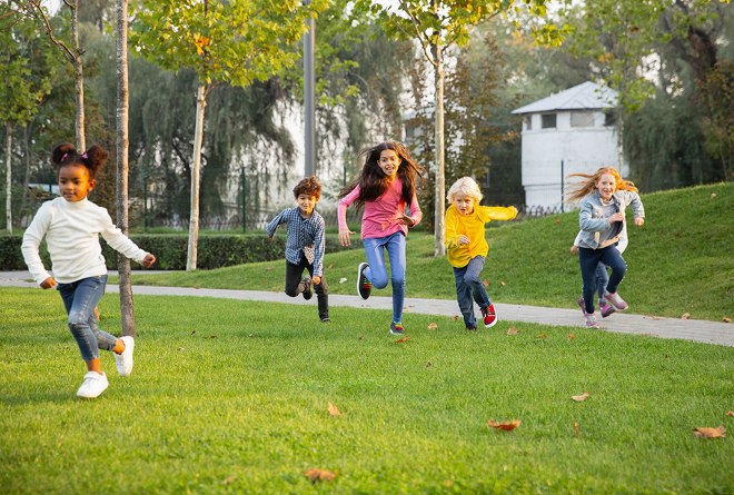 Children running across a park lawn